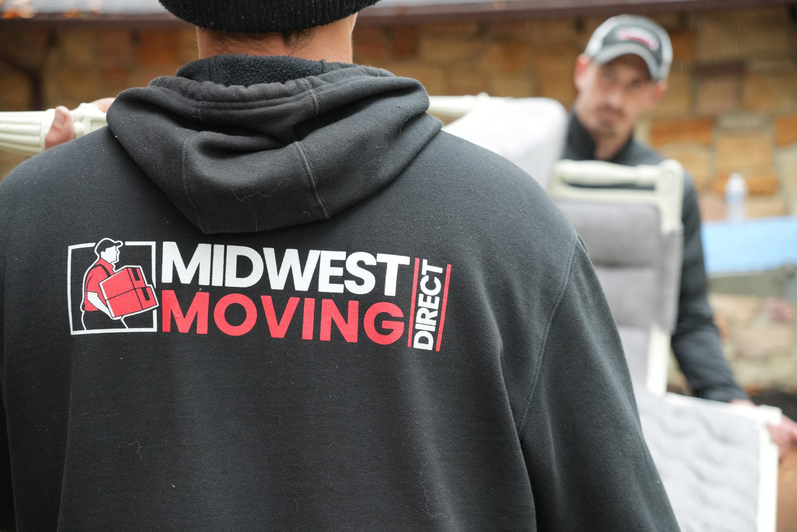 Midwest Moving Direct employee wearing branded hoodie, carrying moving items, representing professional moving services in Akron, OH.