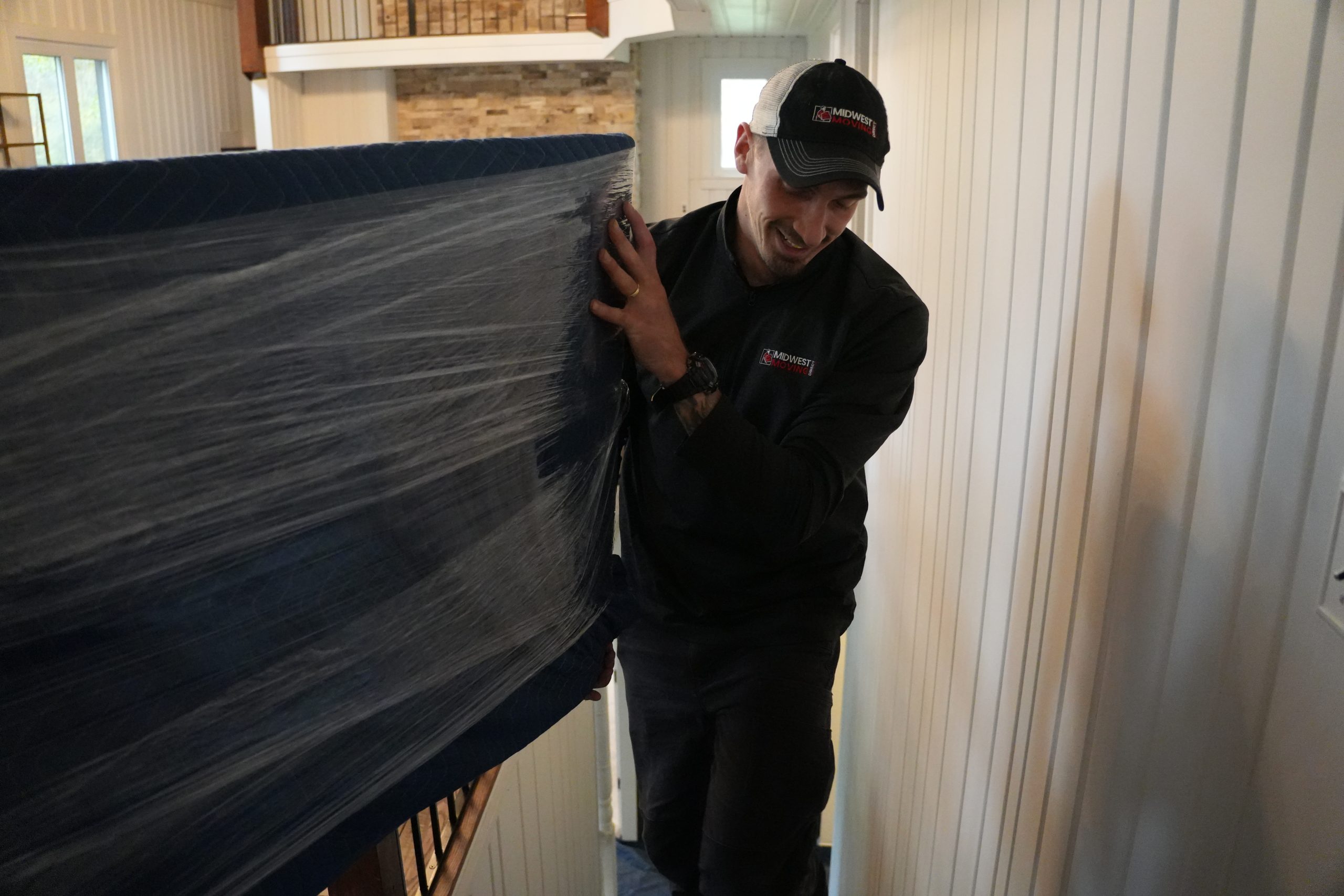 Midwest Moving Direct mover carefully transporting a wrapped couch through a residential hallway, showcasing professional moving services in Northeast Ohio.